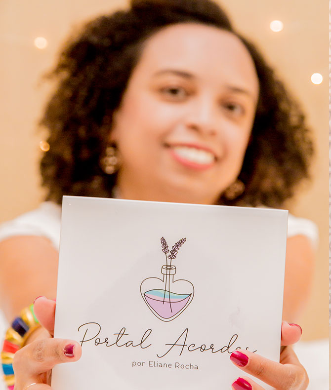 Fotografia de Eliane Rocha segurando um azulejo decorado com a logotipo e nome Portal Acordes